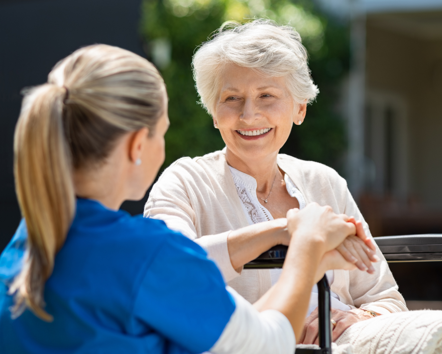 A nurse speaks to an elderly woman in a wheelchair.